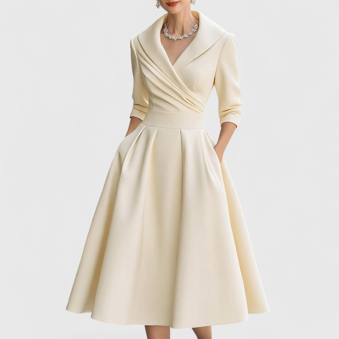 Pale cream dress, front view with a pleated wrap bodice, three-quarter sleeves and flared skirt.