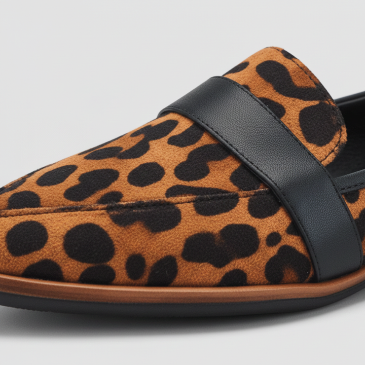Close-up detail of a leopard-print loafer toe with a stitched black leather strap and a thin wooden-look sole edge. 6