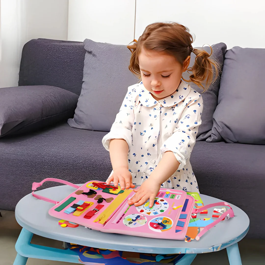 Young girl in a floral dress standing at a small table and touching the clock page of the open pink felt book. 5