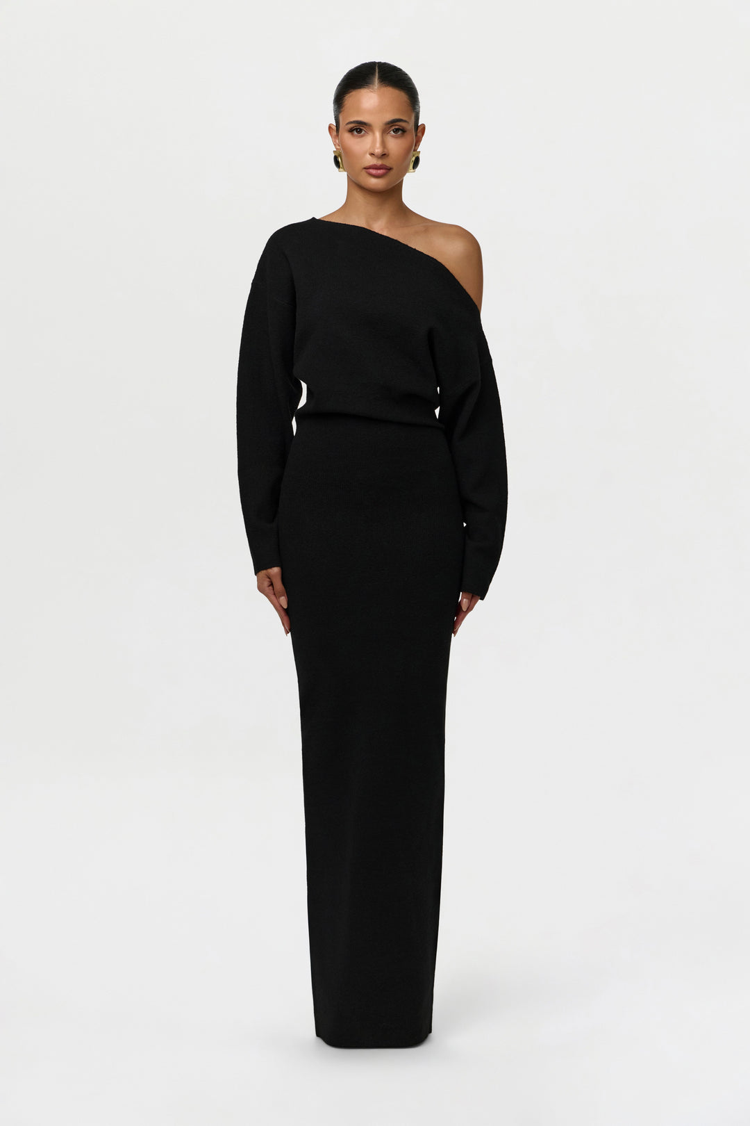 Model faces the camera in the beige off-the-shoulder maxi knit dress with long sleeves.