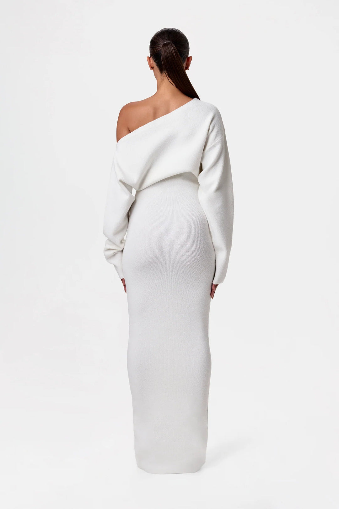 Back view of the white knit maxi dress, showing the exposed shoulder, sleeve shape and slim fit through the hips.