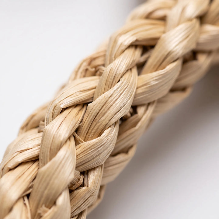 Extreme close-up of a braided natural straw strip, showing the twisted tan fibers and woven texture against a soft white background. 3