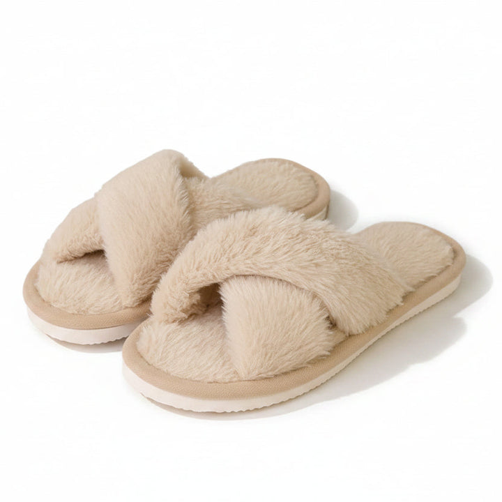 Pair of beige faux fur crossband slippers with a thin white sole on a plain background 1