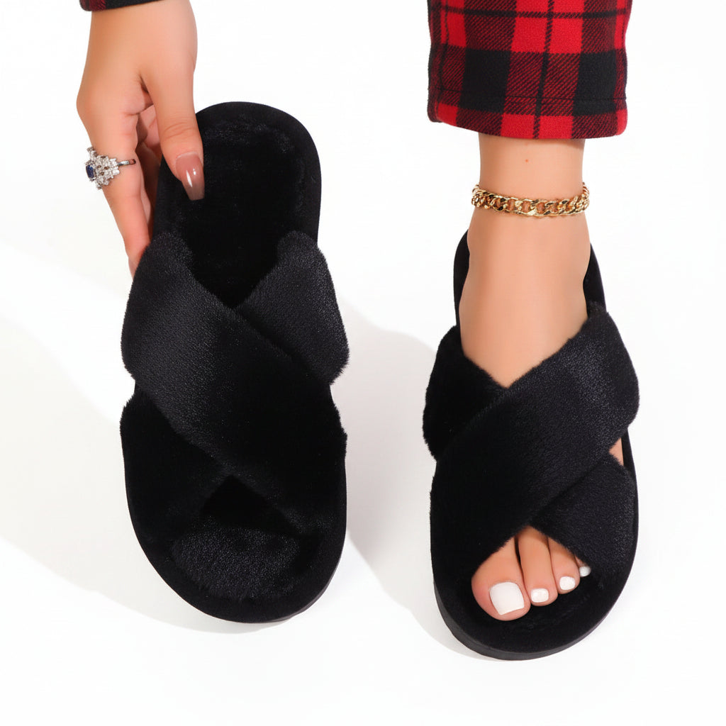 Black plush crossband slippers, one worn with red plaid pants and one held up 9