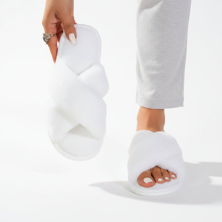 White fluffy crossband slippers, one worn with gray pants and one held up by hand 6