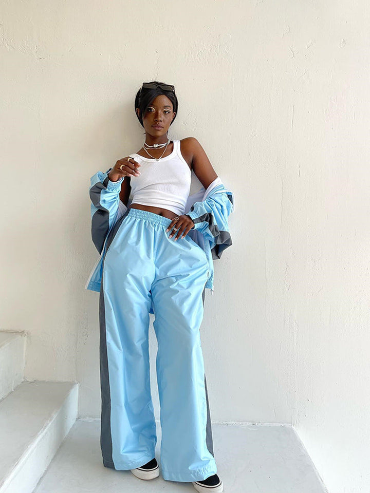 Women's windbreaker tracksuit set in pale blue and gray, another view with the jacket slipped off the shoulders.