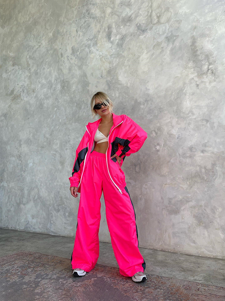 Women's windbreaker tracksuit set in hot pink and dark gray, full-length view with the jacket open.