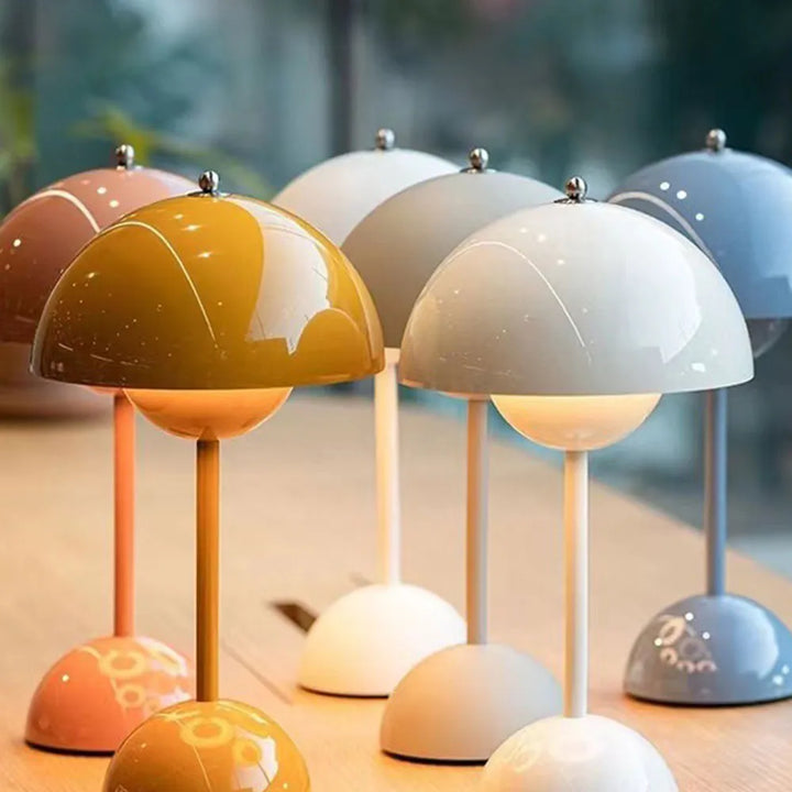 Another view of dome lamps in mustard, white, gray, pink and blue on a wooden table.