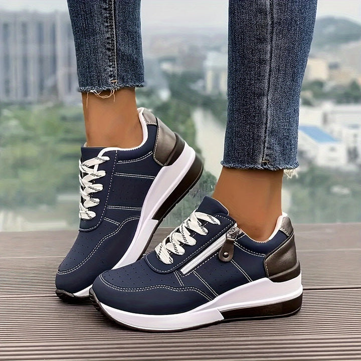Navy blue wedge sneakers with white laces, side zipper and metallic heel tab