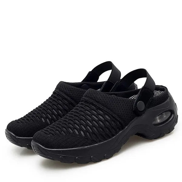 Pair of all-black mesh clogs with a matching black air-cushion sole and snap heel straps on a white background.