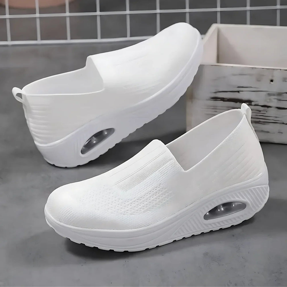 White knit slip-on shoes with a chunky sole and visible air cushion.