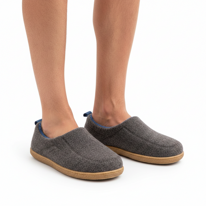 Legs wearing charcoal gray felt slippers with blue lining at the opening and flat tan soles.