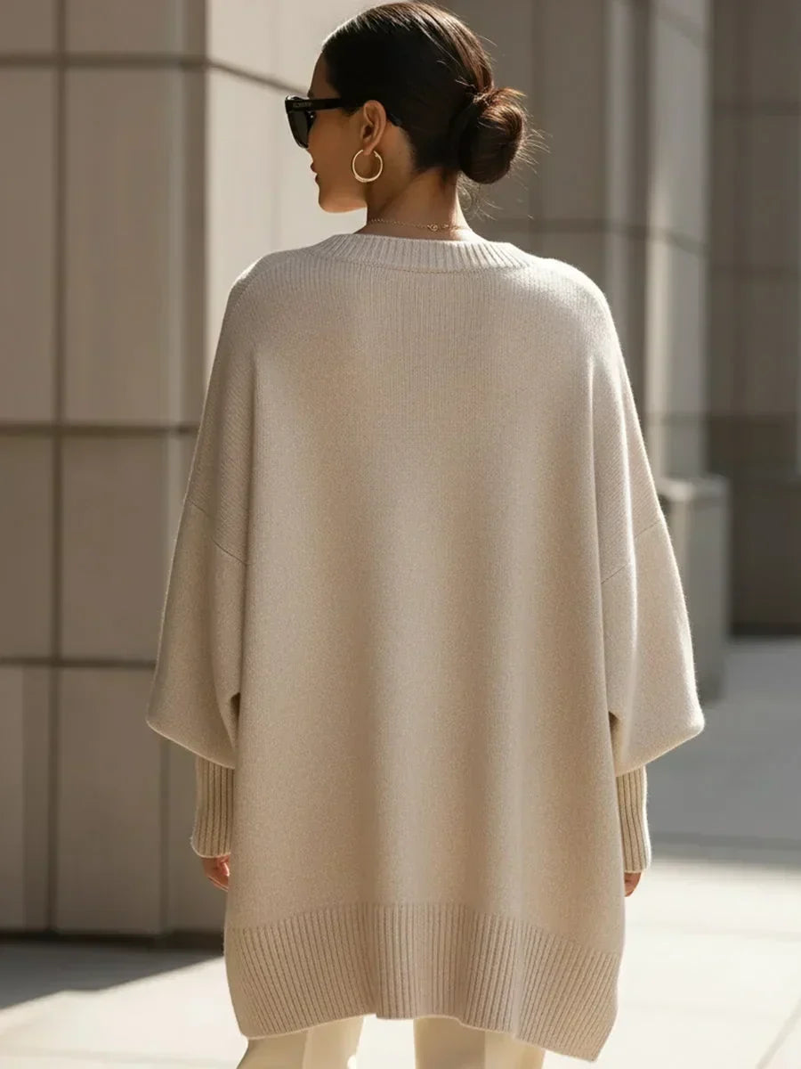 Back view of the beige oversized sweater on a model with a low bun and sunglasses 4