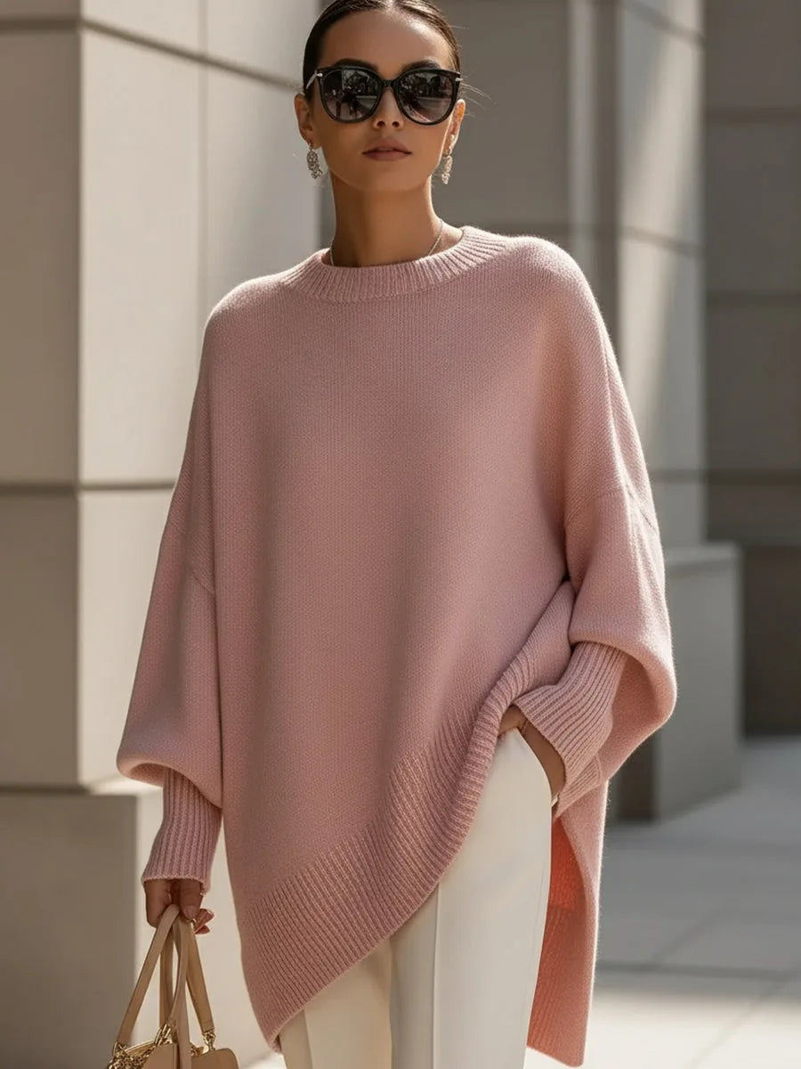 Model wearing the dusty pink oversized sweater with sunglasses, white pants and a tan handbag 11