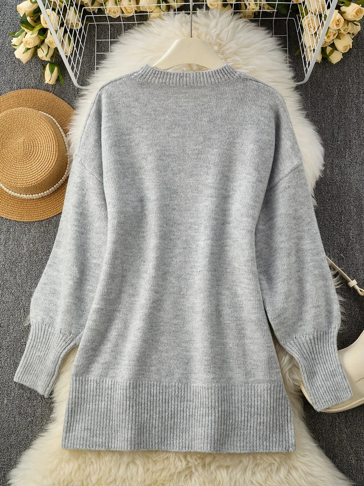 Flat lay of the light gray sweater back on a white fluffy rug beside a straw hat 10