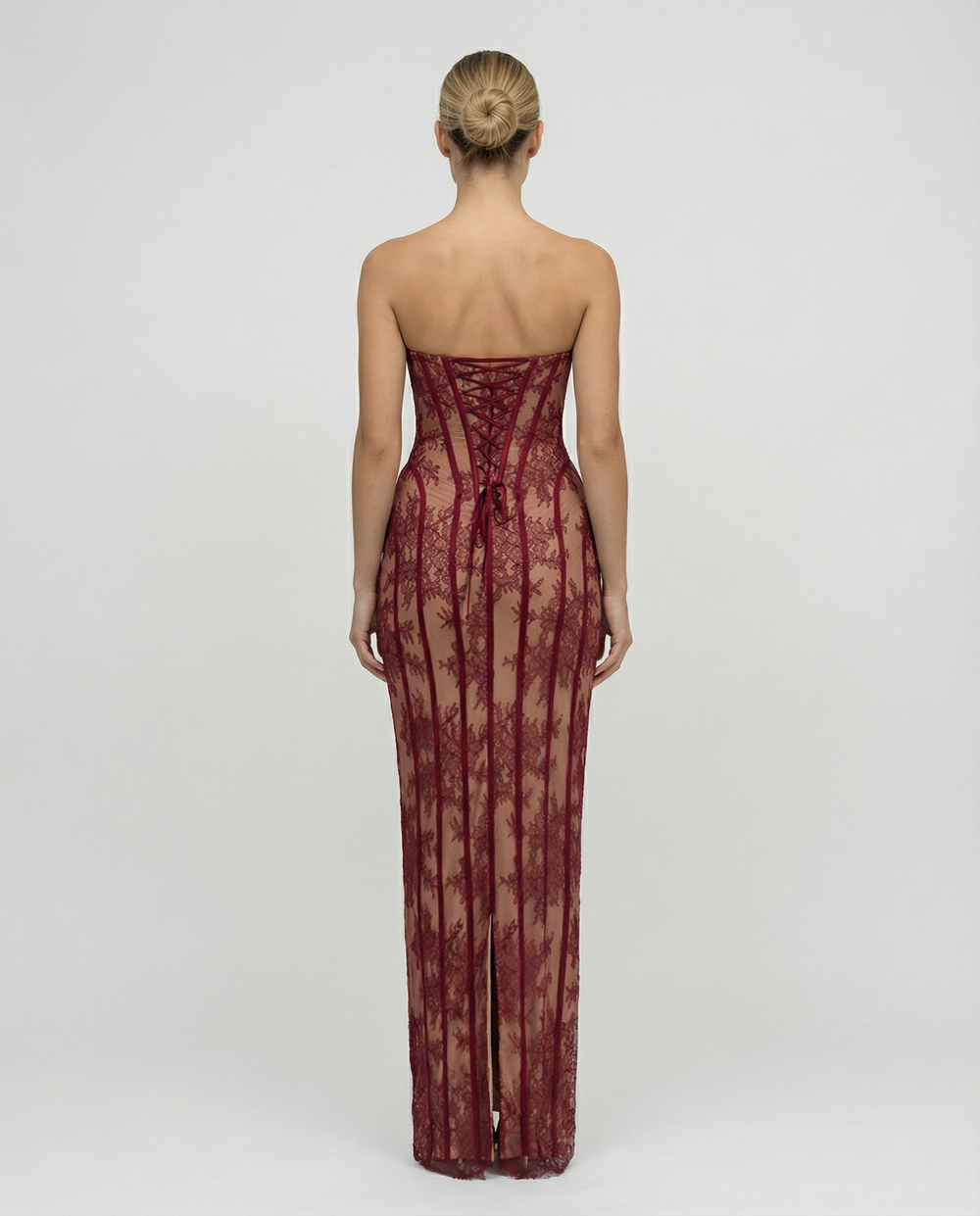 Back view of the red lace maxi dress showing the lace-up corset back, strapless cut and a slit at the hem.
