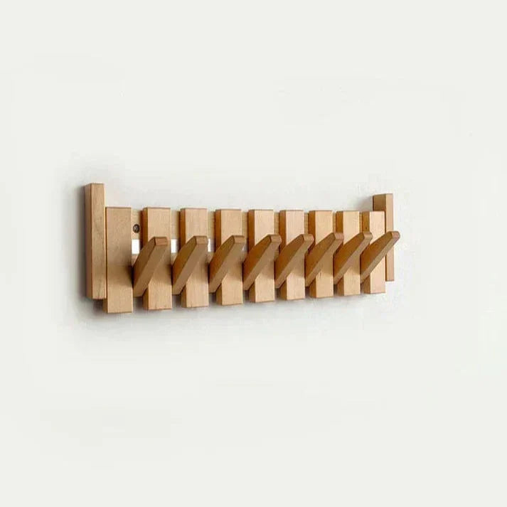 Light natural wood wall rack with seven folding hooks all pulled out at an angle against a white wall. 9