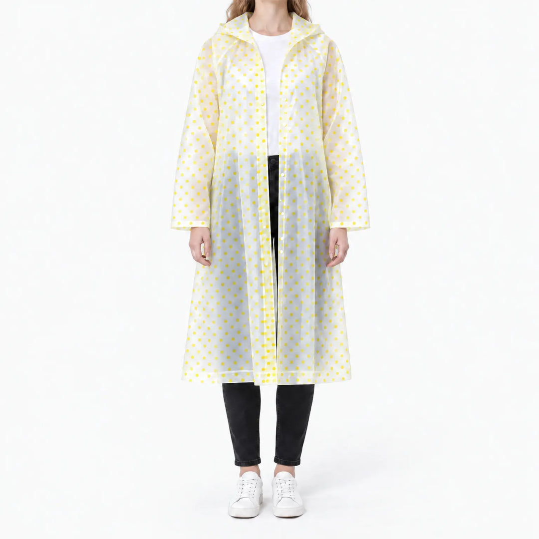 Front view of a woman in a translucent long raincoat with yellow polka dots, snap front open over a white tee and black jeans. 11