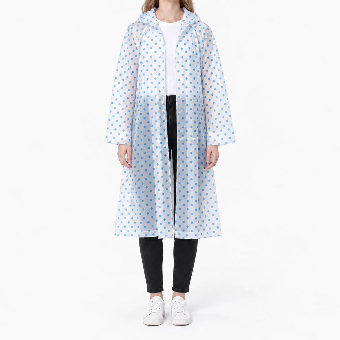 Front view of a woman in a translucent long raincoat with blue polka dots, hood down, worn open over a white tee. 9