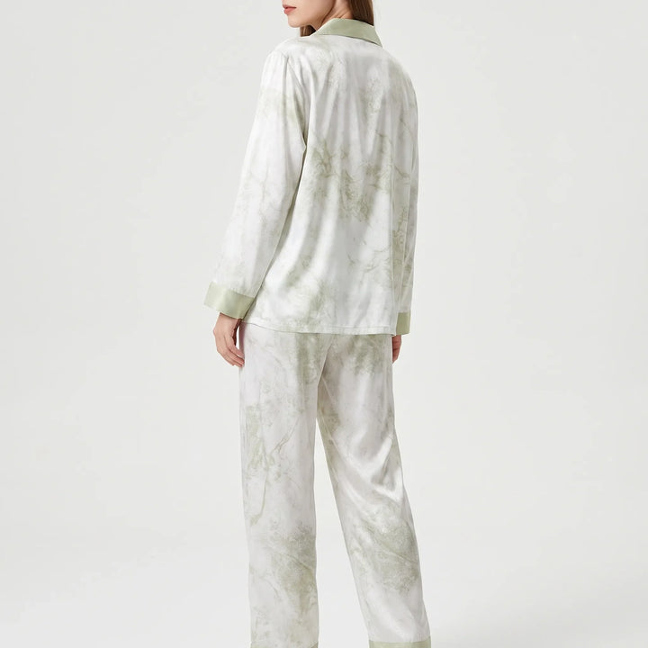 Back view of the model wearing the white and green marbled pajama set, showing the plain back and green cuffs. 3