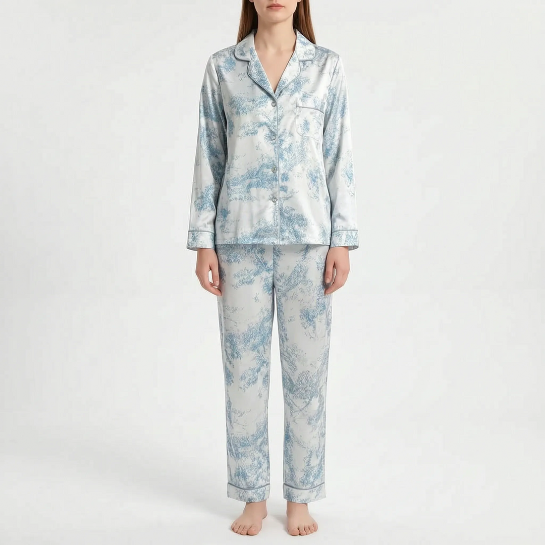 Model standing in a pajama set with a light blue and white pastoral scene print and piped collar, cuffs and pocket. 8
