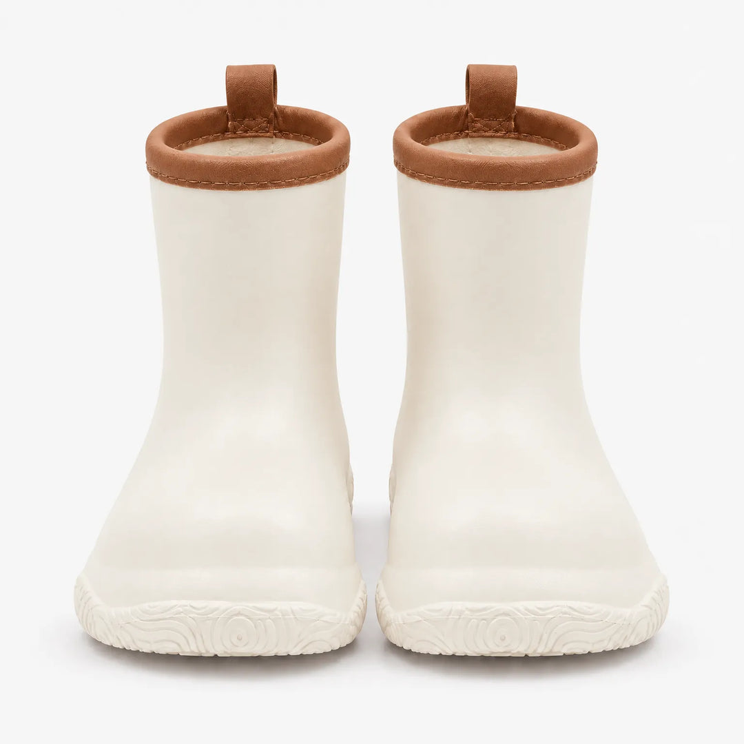 Front view of cream white rain boots with brown collars and pull loops, showing the swirl-patterned soles. 10