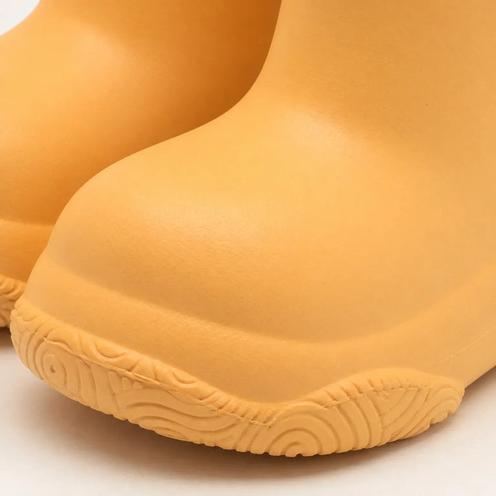 Close-up of an orange boot toe showing the smooth rounded shape and the swirl-patterned tread along the sole edge. 6