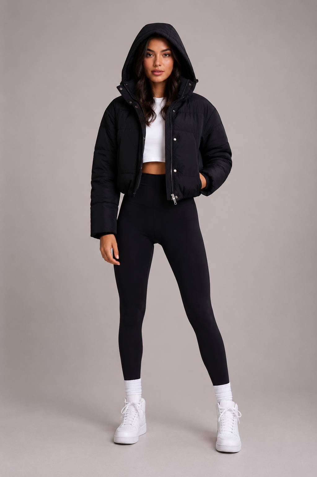Black cropped puffer jacket another view with the hood up and one hand in a pocket.