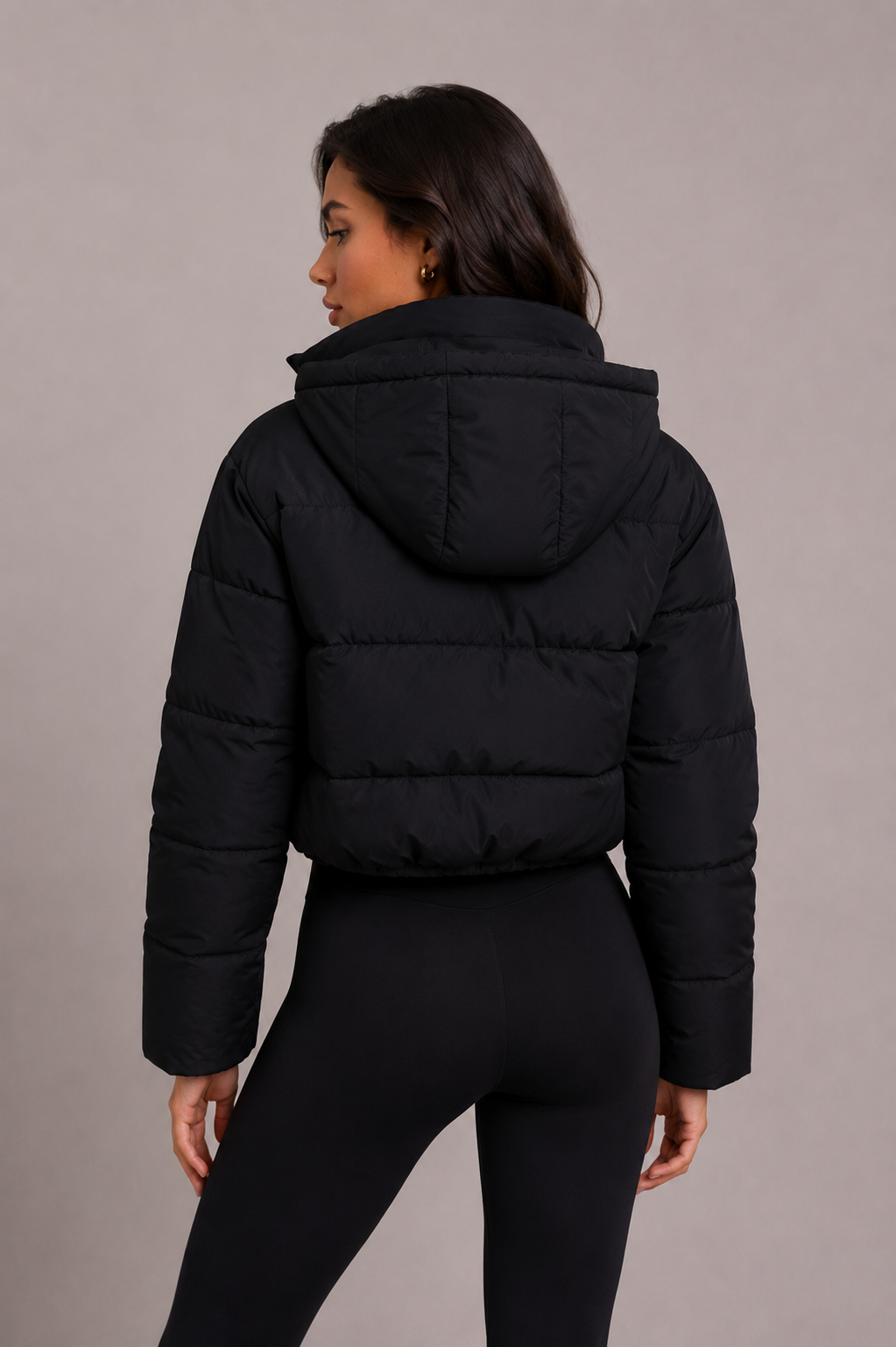 Black quilted jacket back view showing horizontal quilting, folded hood and cropped hem.