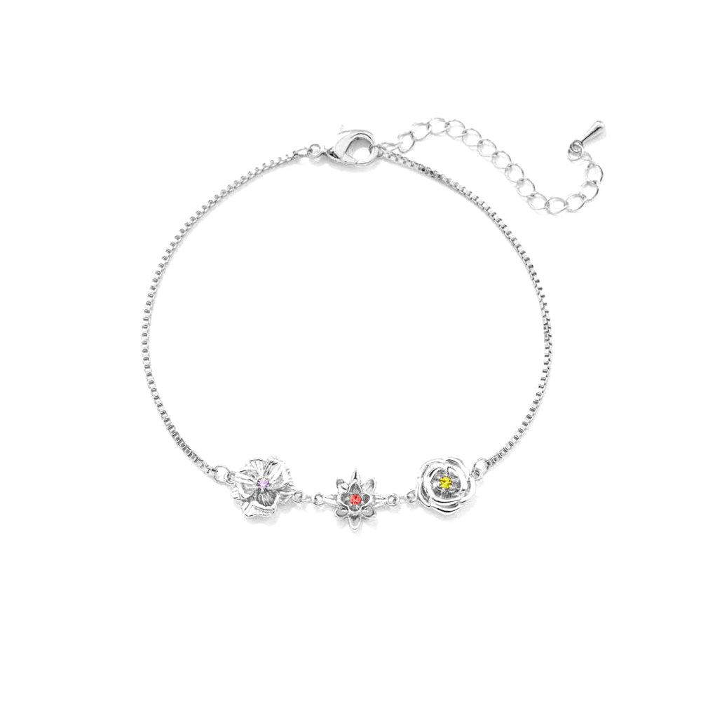 Silver-tone birth flower bracelet with three flower charms and an extender chain, laid flat on white.