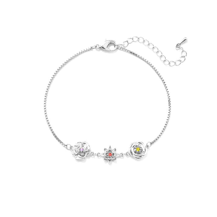 Silver-tone birth flower bracelet with three flower charms and an extender chain, laid flat on white.