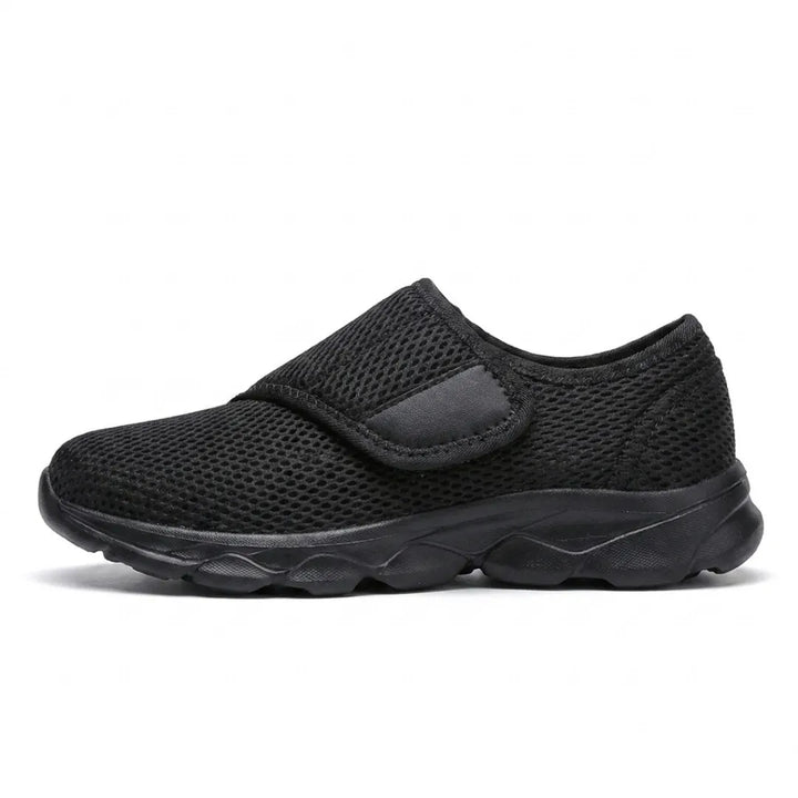 Side view of an all-black mesh shoe with a black sole and a single hook-and-loop strap 10