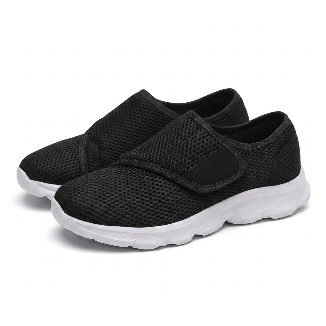 Pair of black mesh walking shoes with white soles and wide hook-and-loop straps, seen at an angle 25