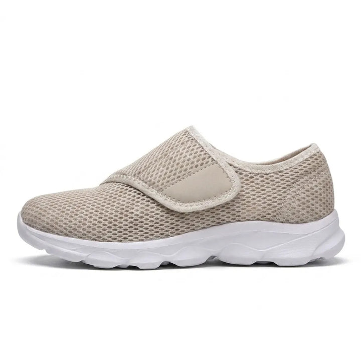 Side view of a beige mesh shoe with white sole and wide hook-and-loop strap across the instep 28