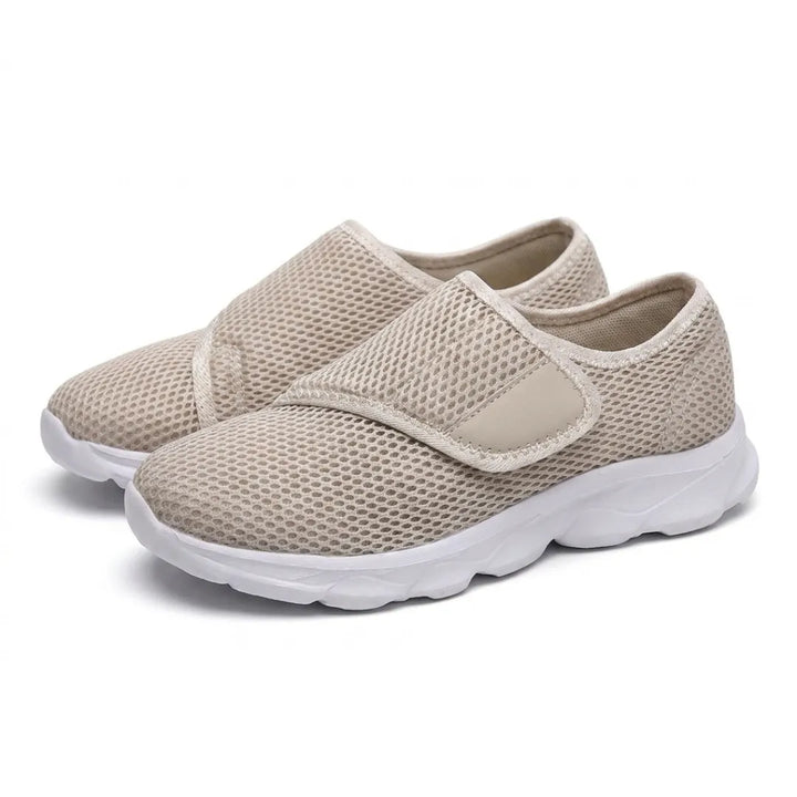 Pair of beige mesh walking shoes with white soles and wide hook-and-loop straps, seen at an angle 34