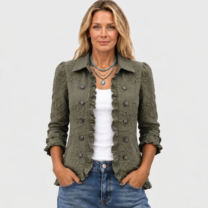 Olive green jacket worn open over a white top with hands in jeans pockets.