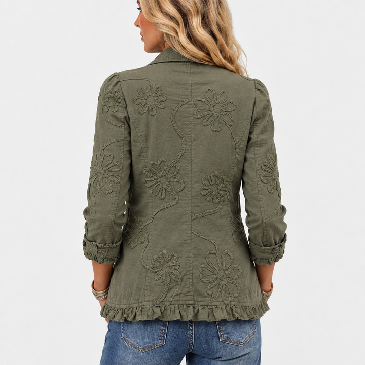 Back view detail of the olive green jacket with large embroidered flowers, vines, and ruffled hem.