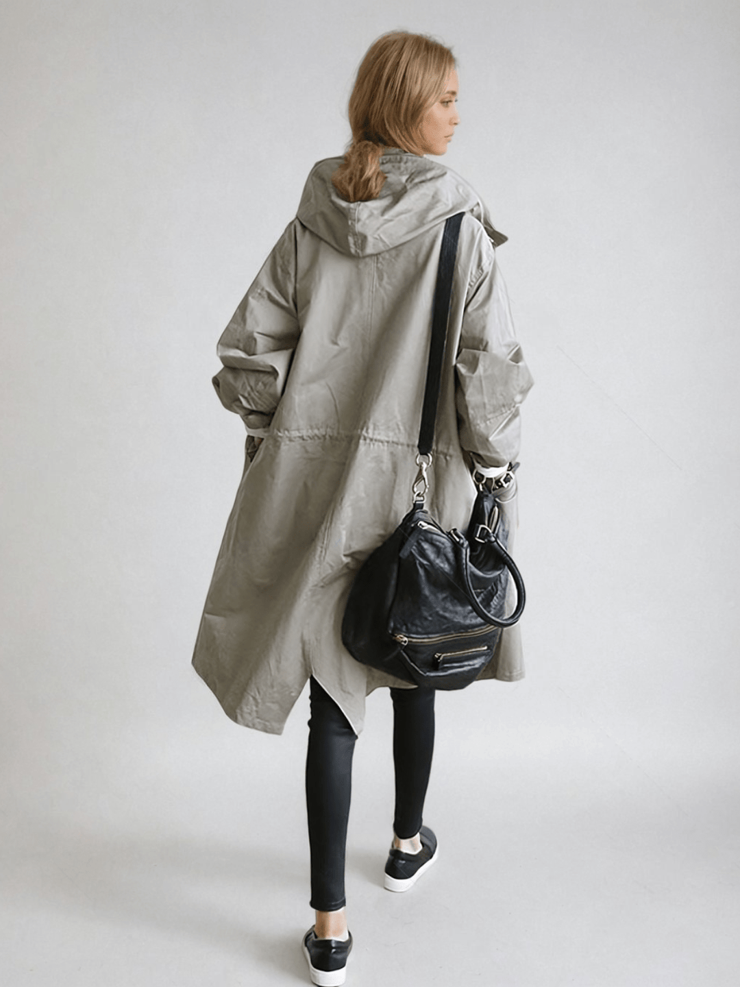 Back view of the gray hooded coat, showing the drawstring waist seam, with a black shoulder bag 4