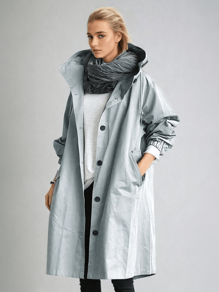 Model in the pale gray-blue hooded coat with a glossy finish, worn open over white with a scarf 5