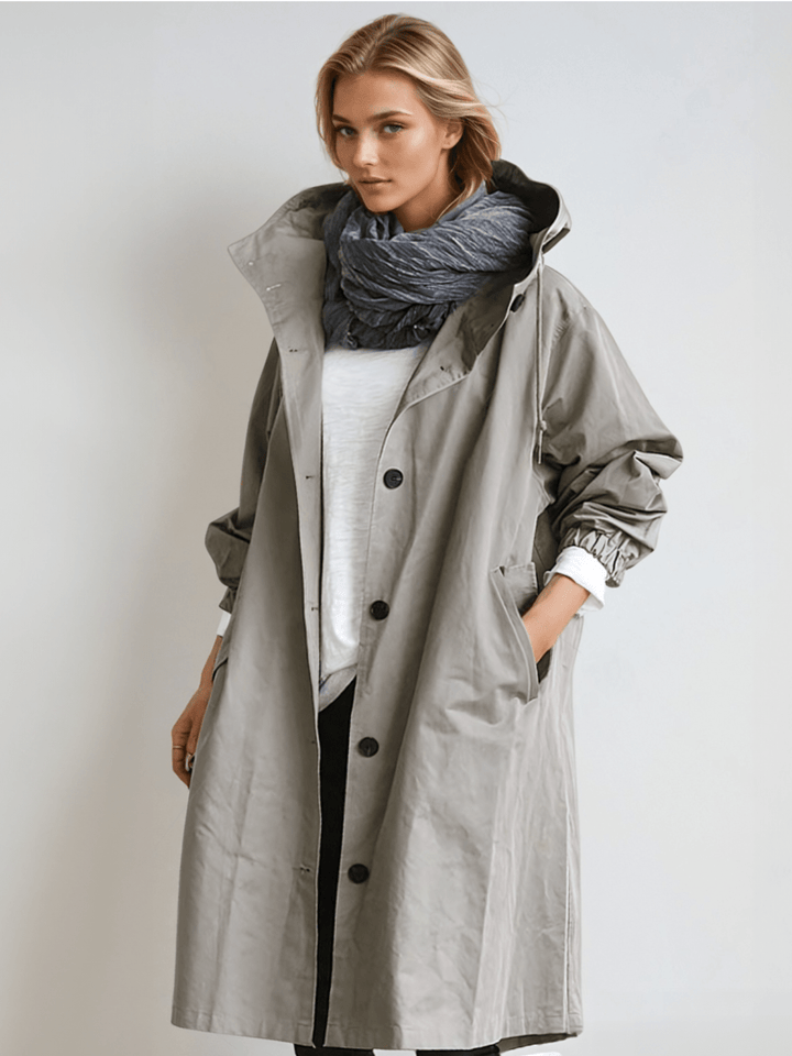 Model in the gray hooded button-front coat, open over a white top and dark scarf, hand in pocket 1