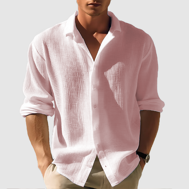 Man wearing the textured shirt in soft blush pink, sleeves rolled, hands in khaki pants pockets 4