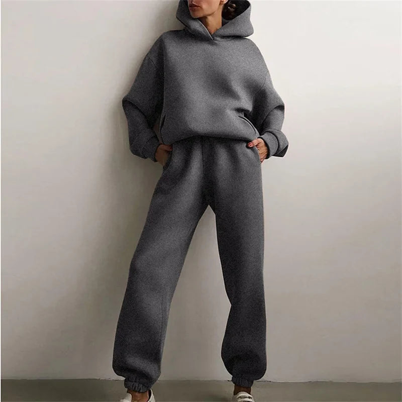Full-length view of a model in a dark gray hoodie and cuffed joggers, hands in pockets 2