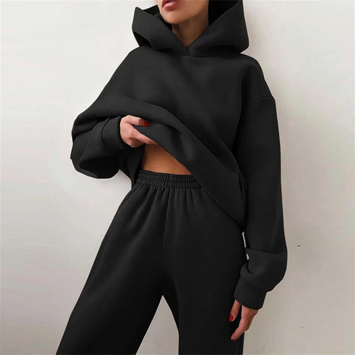 Model in a black oversized hoodie and wide elastic-waist pants, one hand holding the hem 3