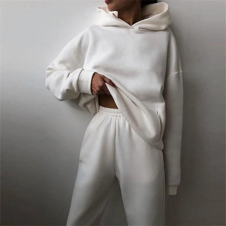 Model in a white fleece hoodie and matching joggers, hand on the hem, side pocket visible 4