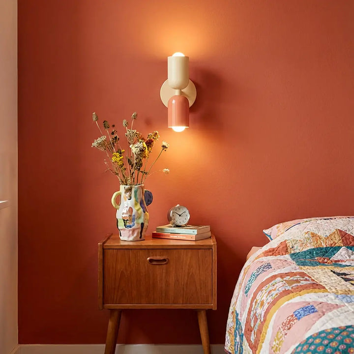 Retro wall lamp in cream and coral on a terracotta wall above a wooden nightstand