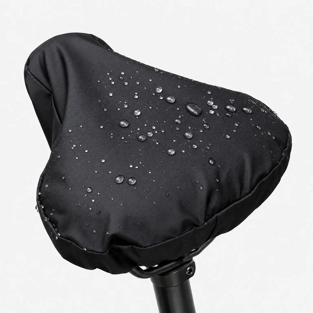 Close-up of the black cover on a saddle against a white background, with water droplets beading on the surface. 2
