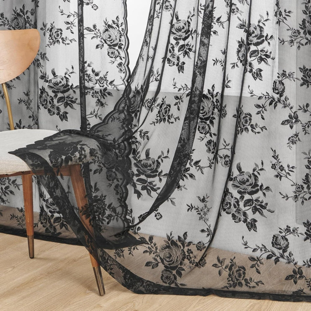 Black floral lace panel draped over a wooden chair, showing the bold pattern and the scalloped side edge up close.