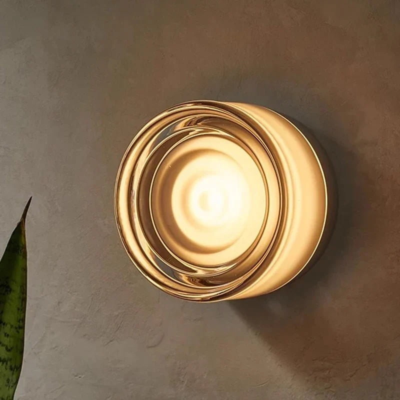 Close-up detail of a lit round wall light with concentric clear glass rings and a frosted center.