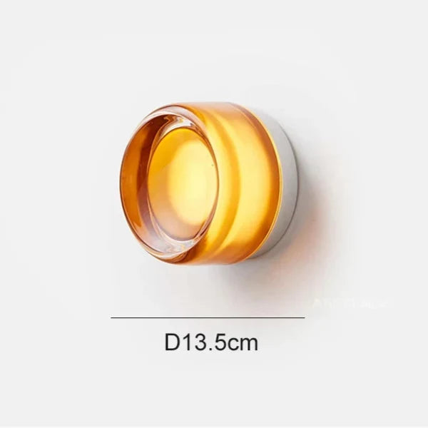 Amber glass round wall light shown lit on a white background with a 13.5 cm diameter line.