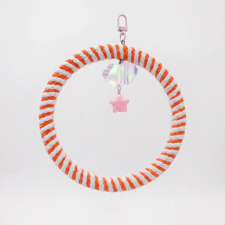 Hanging ring swing wrapped in orange and white cotton rope, with a pink clasp, iridescent cloud charm and pink star bead. 1